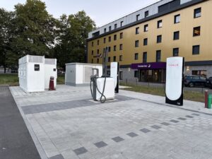 Vue d'ensemble de la station de superchargeur V4 de Tesla à Lindau, en Allemagne, montrant deux bornes de recharge équipées d'un aspirateur central pour le nettoyage des voitures pendant la recharge.